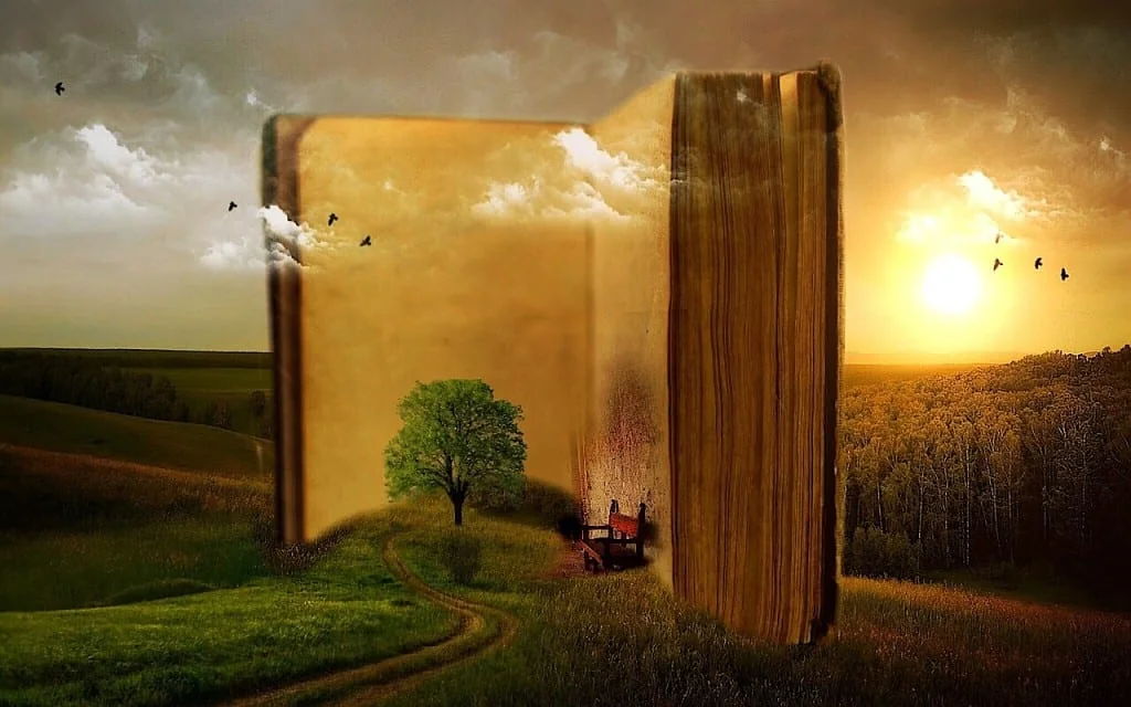 Surreal image of a giant open book standing in a green landscape at sunset, with a tree and path on its pages