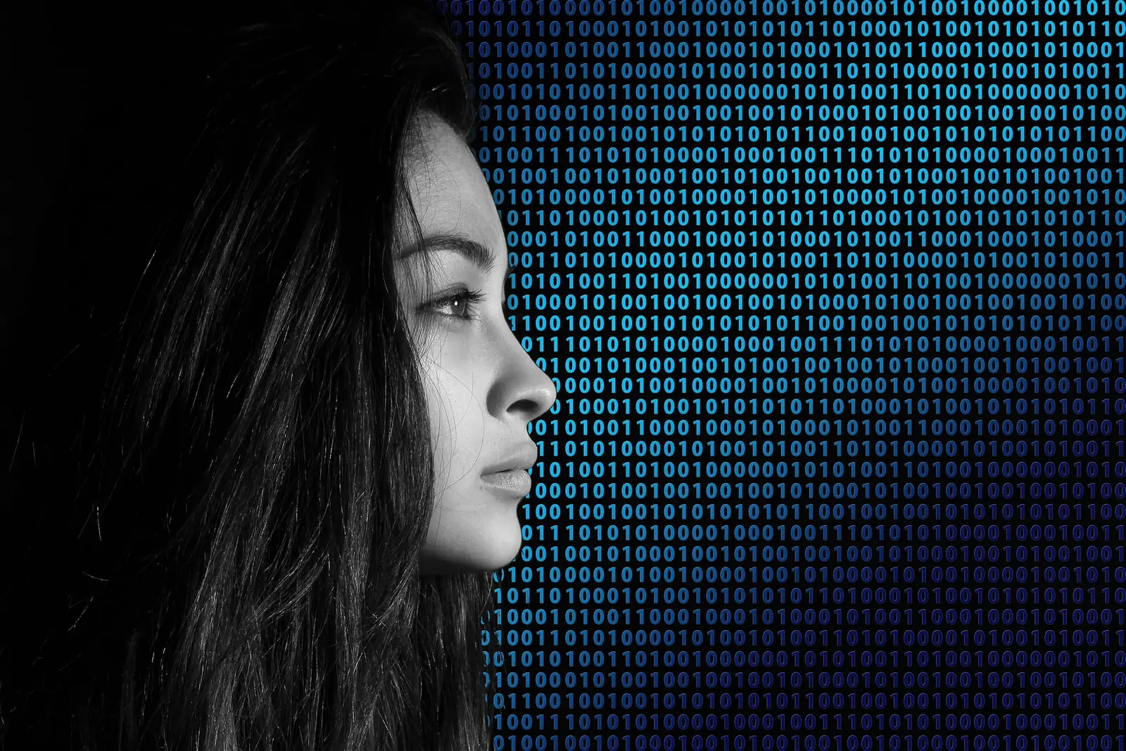 Profile of a woman in black and white facing a wall of glowing blue binary code