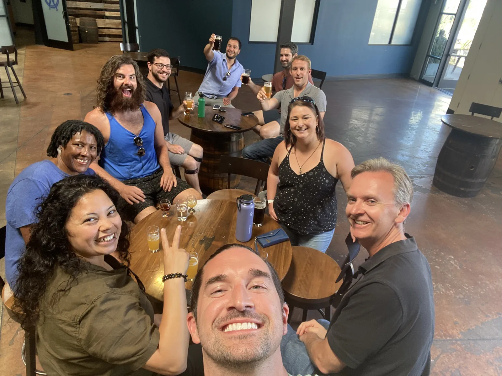 The Digital Empathy team around barrel tables at a taproom, everyone grinning at the camera